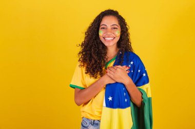 Genç siyah Brezilyalı kadın, futbol fanatiği. Brezilya bayrağıyla. Göğüs göğüse, minnettarız..