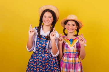 Festa Junina 'nın tipik kıyafetlerini giyiyorlar. Parmaklar çapraz, bükük, özlem dolu.