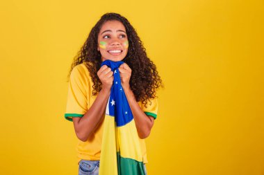 Genç siyah Brezilyalı kadın, futbol fanatiği. Brezilya bayrağıyla. Endişeli.