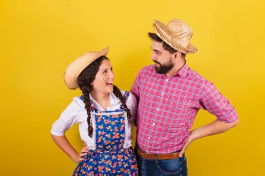 Baba ve kızı Festa Junina için tipik kıyafetler giyiyor. Elleri belinde. Arraia partisi için.