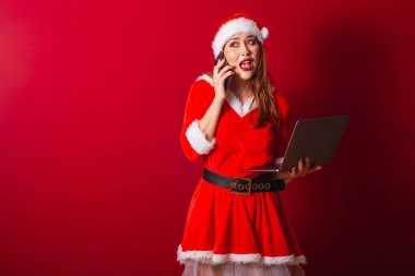 Güzel Brezilyalı kızıl saçlı kadın, Noel kıyafetleri giymiş, Noel Baba. Not defteri ve akıllı telefon tutuluyor, meşgul.