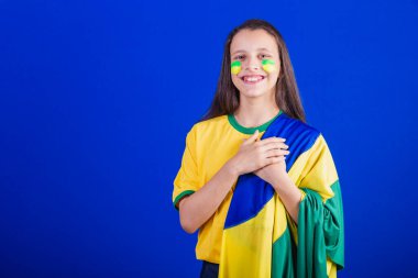 Genç bir kız, Brezilyalı bir futbol taraftarı. Bayrak gibi giyinmiş, milli marşı söylüyor. Minnettarlık.