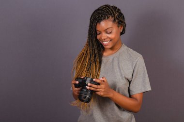 Genç afro Brezilyalı kadın, fotoğrafçı, gülümseyen, elinde fotoğraf makinesi olan..