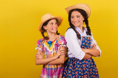 Festa Junina için tipik kıyafetler giyiyorlar. Kollar çapraz, mutlu bir şekilde gülümsüyor. Arraia partisi için.
