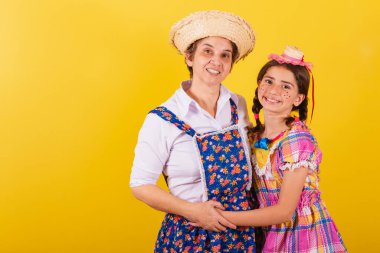 Büyükanne ve torun tipik Festa Junina kıyafetleri giymişler. Sarılmak ve gülümsemek..