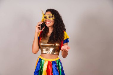 Güzel siyah Brezilyalı kadın, karnaval kıyafetleri giyiyor, akıllı telefonlu sesli arama yapıyor..