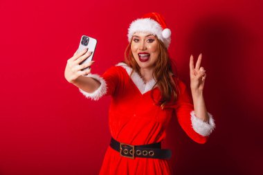Güzel Brezilyalı kızıl saçlı kadın, Noel kıyafetleri giymiş, Noel Baba. akıllı telefondan video çağrısı.