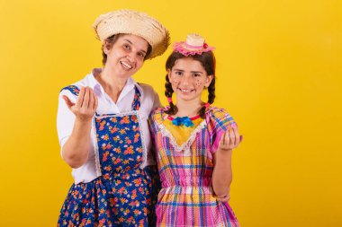 Büyükanne ve torun tipik Festa Junina kıyafetleri giymişler. Ellerinle çağır, davet et, buraya gel..