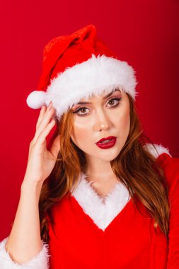 Güzel Brezilyalı kızıl saçlı kadın, Noel kıyafetleri giymiş, Noel Baba. Yüzün dikey yakın çekim görüntüleri, kamera için modelleme..