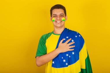 Genç Brezilyalı futbol fanatiği. Yeşil giyinmiş, eli göğsünde, minnettarlık, milli marş.