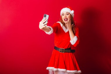 Güzel Brezilyalı kızıl saçlı kadın, Noel kıyafetleri giymiş, Noel Baba. akıllı telefondan video çağrısı.