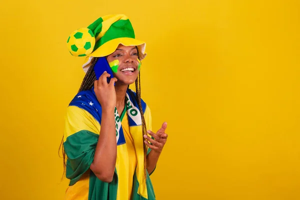 黒人女性の若いブラジル人サッカーファン 音声通話にスマートフォンを使っています 話すこと — ストック写真