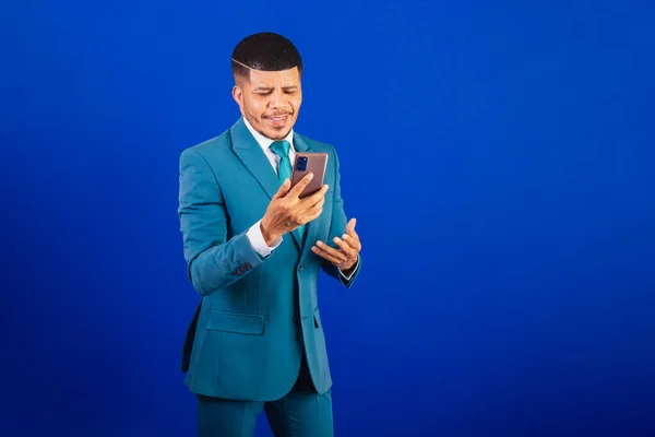Brazilian black man, dressed in a suit and blue tie. business man. using your smartphone