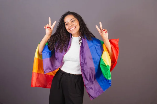 stock image Young Brazilian black woman, sign of peace and love, militancy with LGBT flag, diversity.