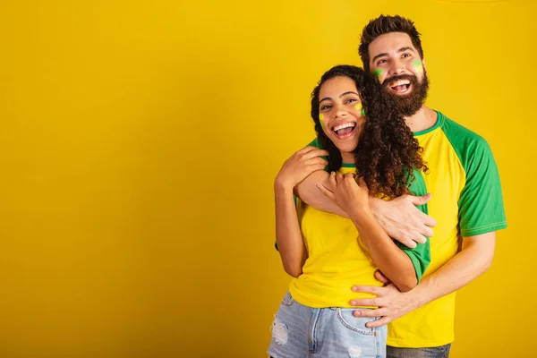 couple of brazil soccer supporters, dressed in the colors of the nation, black woman, caucasian man. together, romantic
