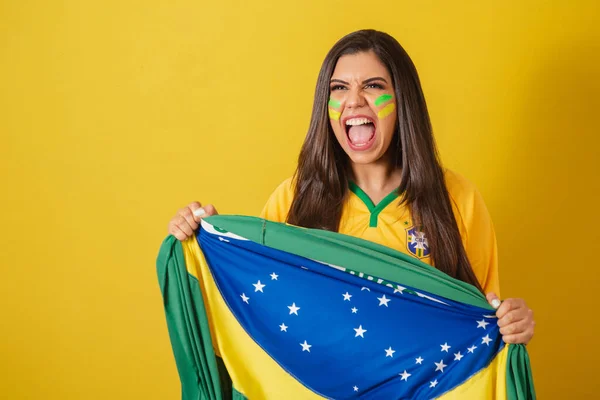 Woman supporter of Brazil, world cup 2022, football championship, holding flag screaming goal and cheering, partying, celebrating.