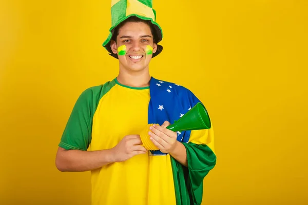 若いブラジル人のサッカーファン 緑の服を着て角を握りブラジルの国旗を胸に — ストック写真