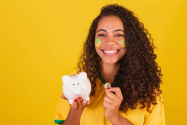 Junge Schwarze Brasilianerin Fußballfan Sparschwein Und Münze Der Hand Finanzen — Stockfoto