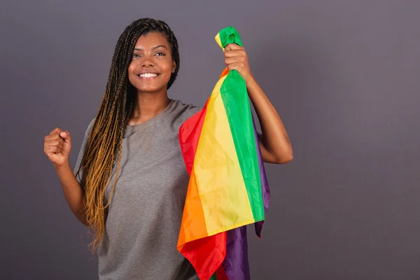 Young afro brazilian woman, holding LGBT, LGBTQ flag, in the form of militancy. Empowerment of diversity.
