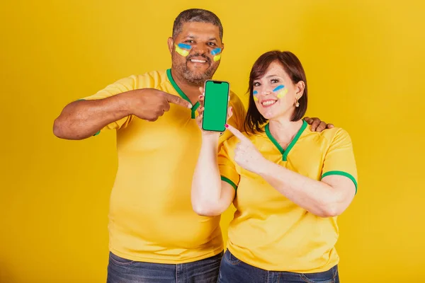 カップル 赤髪の女性と黒の男 ブラジルのサッカーファン スマートフォン オンラインモバイル — ストック写真