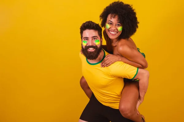 ブラジルのサッカーファンのカップルは ブラジルの色 黒の女性 白人男性に身を包んだ 冗談だよ後ろで恋をして — ストック写真