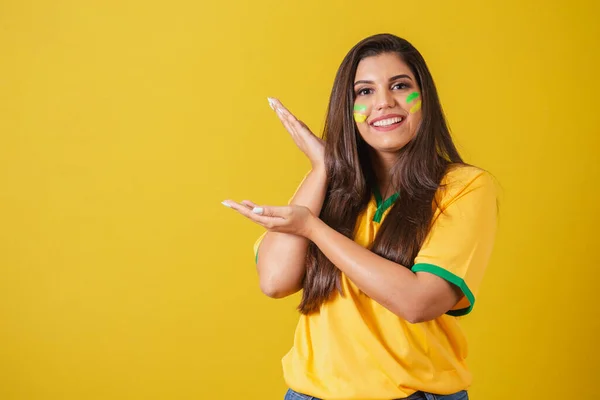 stock image Woman supporter of Brazil, world cup 2022, soccer championship, presenting product with hands to the left.