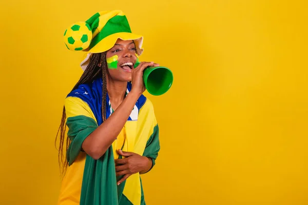 black woman young brazilian soccer fan. using phone pick up to announce something.