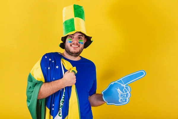 巴西白人男子 足球迷从巴西 戴着帽子 用泡沫手指指向右 — 图库照片