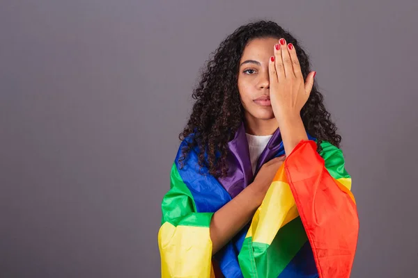 Young black Brazilian woman, covering her eyes, militancy with LGBT flag, diversity, fight against prejudice.