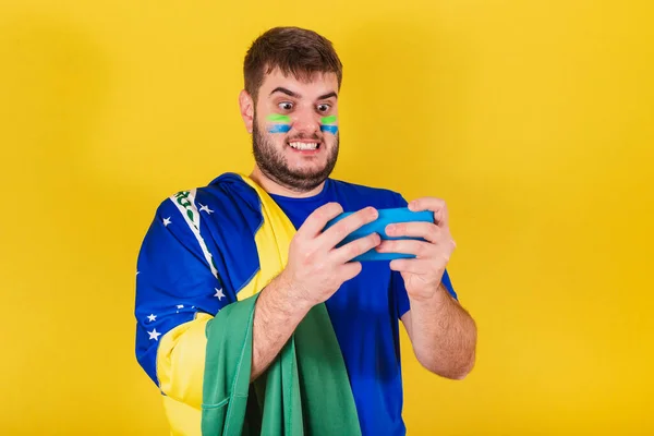 ブラジル出身のブラジル人白人男性サッカーファン携帯電話でゲームをしています — ストック写真