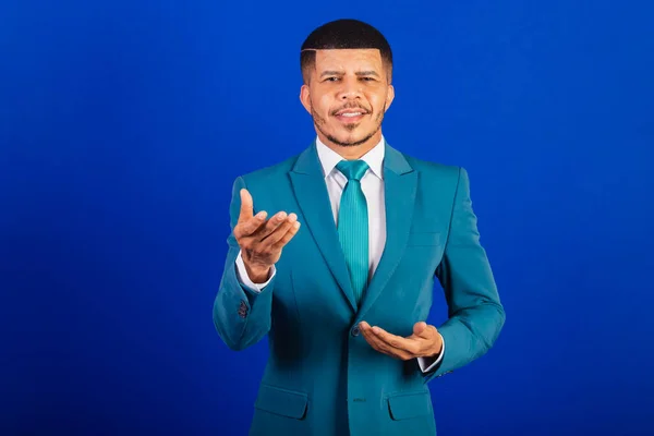Brazilian black man, dressed in a suit and blue tie. business man. presenting something, pointing at camera