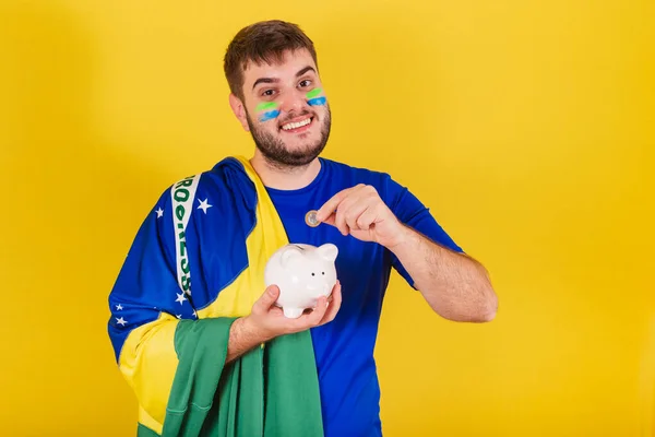 ブラジルの白人男性 ブラジルのサッカーファン 貯金箱 コインを持っています — ストック写真