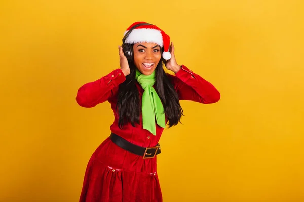 美しい黒ブラジルの女性 クリスマス服を着て サンタクラス ヘッドフォンで音楽を聴く — ストック写真