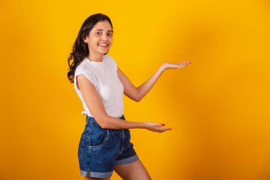 Güzel Brezilyalı kadın sağ tarafa bir şey sunuyor..