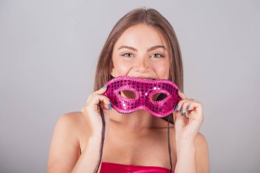 Pembe karnaval kıyafetleri giymiş Brezilyalı sarışın kadın. Yüzüne maske takıyor. Yakın plan fotoğraf..