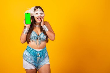 Mavi beyaz karnaval kıyafetleri içindeki güzel Brezilyalı kadın. Akıllı telefonu yeşil ekranlı tutarak.