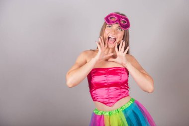 Pembe karnaval kıyafetleri giymiş Brezilyalı sarışın kadın. Rimel sürmek, terfi diye bağırmak, reklam yapmak..