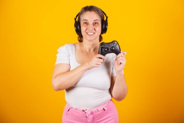 Yetişkin Brezilyalı kadın, anne, video oyunu kumandası, joystick. Oyuncu. Kulaklık takmak, internetten çalmak..