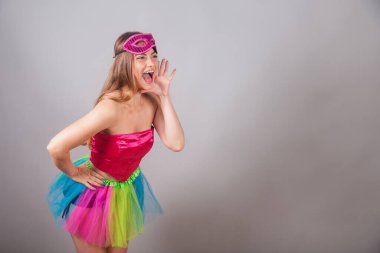 Pembe karnaval kıyafetleri giymiş Brezilyalı sarışın kadın. Rimel sürmek, terfi diye bağırmak, reklam yapmak..