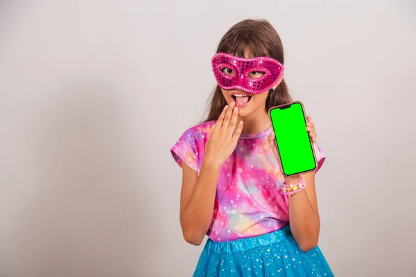 stock image Beautiful Brazilian girl, child, dressed for carnival in Brazil. amazing smartphone with green Chroma screen.