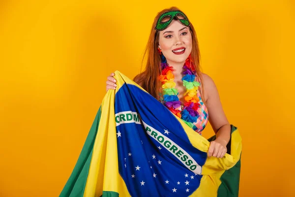 身穿嘉年华服装的巴西红头发 脖子上戴着一条花项链 拿着一面巴西国旗 — 图库照片