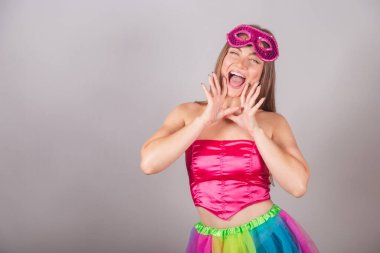 Pembe karnaval kıyafetleri giymiş Brezilyalı sarışın kadın. Rimel sürmek, terfi diye bağırmak, reklam yapmak..