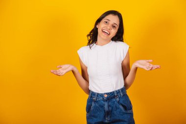 Güzel Brezilyalı kadın şüpheli bir şekilde kollarını açmış. gülümsüyor.