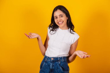 Güzel Brezilyalı kadın şüpheli bir şekilde kollarını açmış. gülümsüyor.