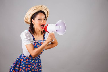 Brezilyalı kadın, kuzeydoğuda, Haziran partisi kıyafetleriyle, hasır şapkalı. Reklam, reklam ve pazarlama için mega telefon kullanmak..