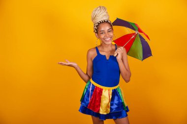 Güzel siyah Brezilyalı kadın, karnaval kıyafetleri giymiş, mavi ve sarı arka plan, çörek ve örgü, beleş şemsiye. Yan tarafta bir şey var..