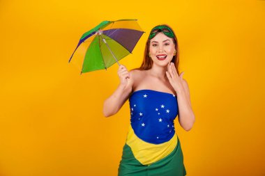 Brezilya bayrağından yapılmış karnaval kıyafetleri ve renkli şemsiyesi olan güzel Brezilyalı kızıl..