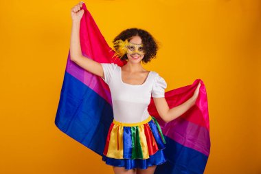 Güzel Brezilyalı kadın, karnaval kıyafetleri, renkli etek ve beyaz gömlek giymiş. Maske takıyor, biseksüel bayrak tutuyor..