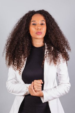 Dikey fotoğraf, güzel siyah Brezilyalı kadın, iş kadını, beyaz takım elbiseli, kameraya bakıyor..