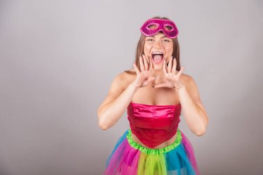 Pembe karnaval kıyafetleri giymiş Brezilyalı sarışın kadın. Rimel sürmek, terfi diye bağırmak, reklam yapmak..